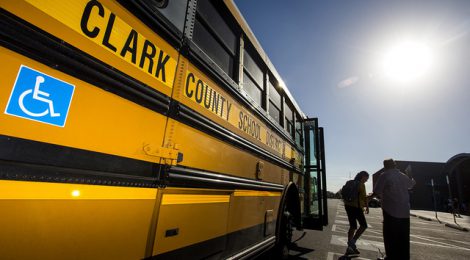 a student getting off of a CCSD school bus meeting a teacher